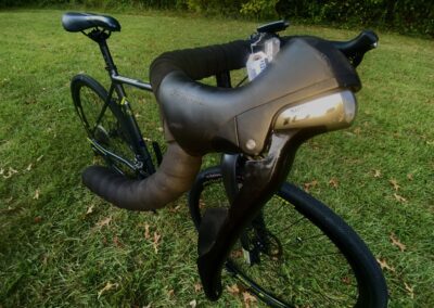 A black bike is parked in a grassy field.